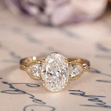 Oval diamond three-stone engagement ring with pear accents in 14K yellow gold