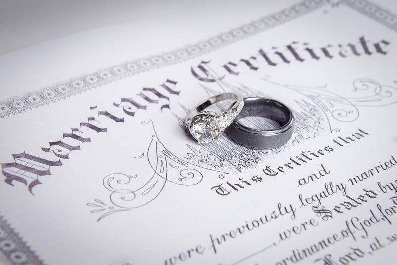 marriage license beneath wedding ring set