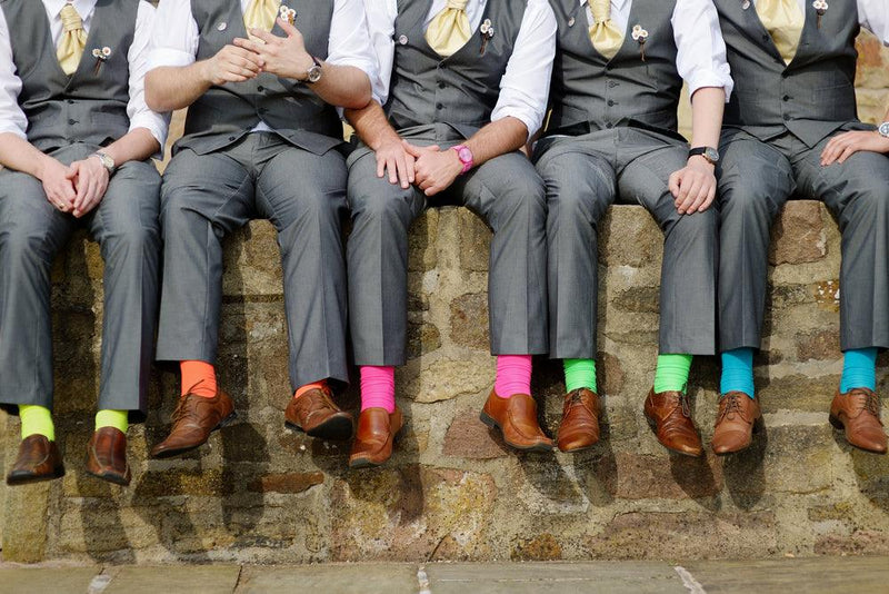 groomsmen sitting on wall wearing colorful socks