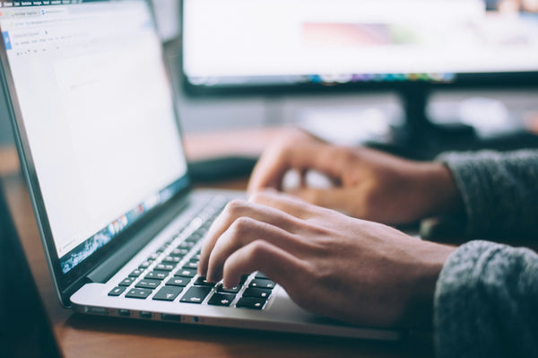 Man's hands typing on laptop.