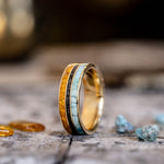 Gold ring with embedded stones on a textured surface