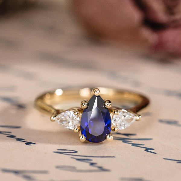 Pear cut lab-grown blue sapphire engagement ring with diamond accents in 14K yellow gold