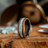 Wooden ring with turquoise inlay on a wooden surface