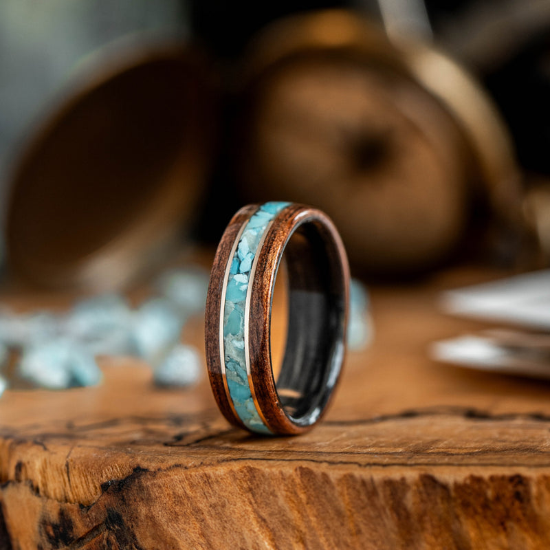 Wooden ring with turquoise inlay on a wooden surface