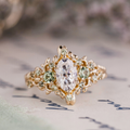 Custom Floral Vine Inspired Oval Moissanite Engagement Ring with Green Sapphire Accents