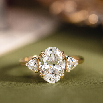 Custom three stone oval diamond engagement ring with trillion cut diamonds