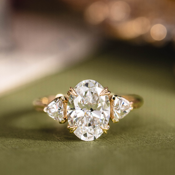 Custom three stone oval diamond engagement ring with trillion cut diamonds