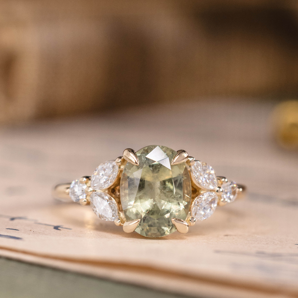 Oval green sapphire engagement ring with marquise diamond accents in 14K yellow gold