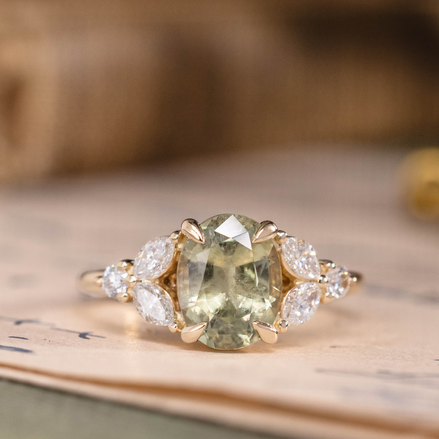 Oval green sapphire engagement ring with marquise diamond accents in 14K yellow gold