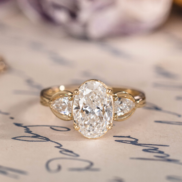 Oval diamond three-stone engagement ring with pear accents in 14K yellow gold