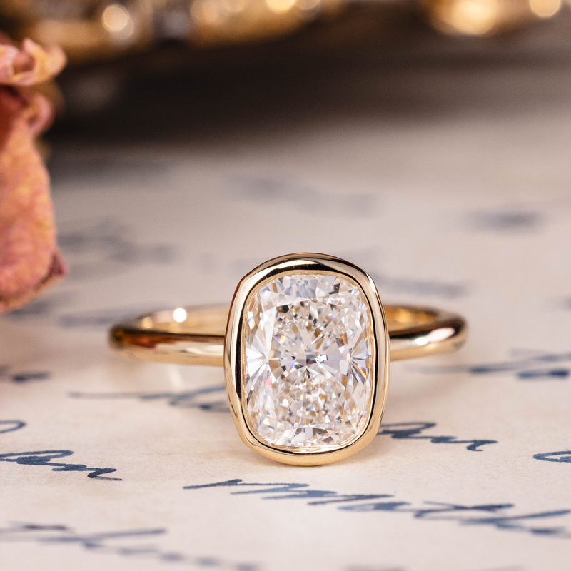 Cushion cut diamond solitaire engagement ring, bezel set in gold