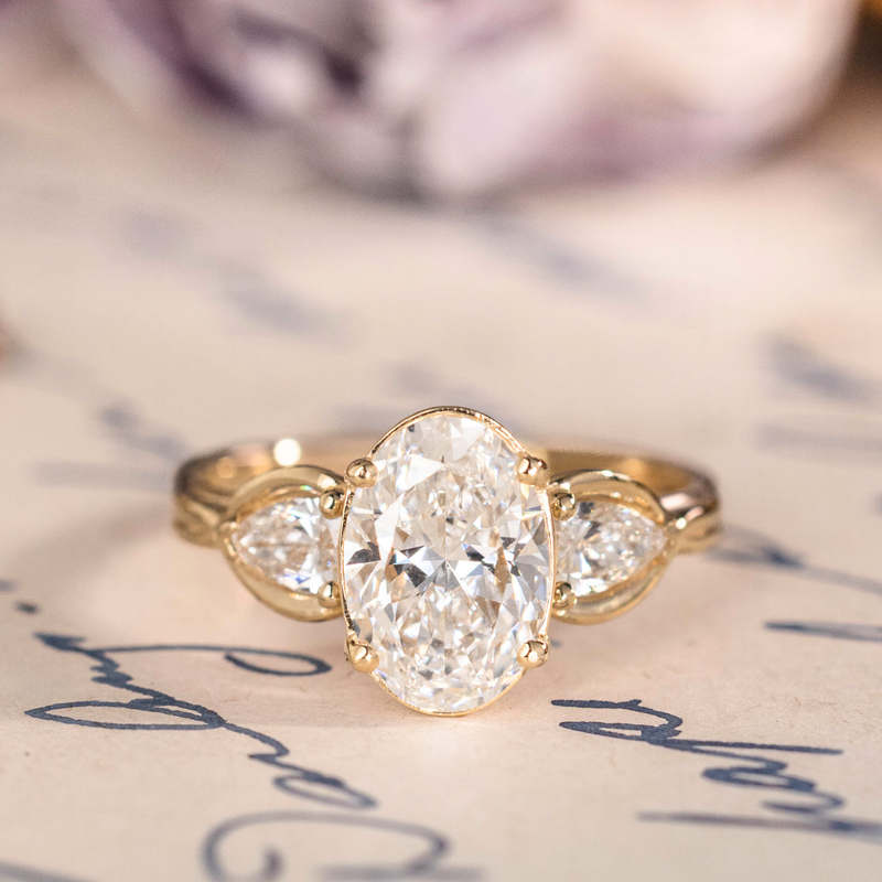Oval diamond three-stone engagement ring with pear accents in gold