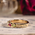 Vintage marquise family ring with ruby, tanzanite, peridot, tourmaline, and diamond accents in 18K yellow gold
