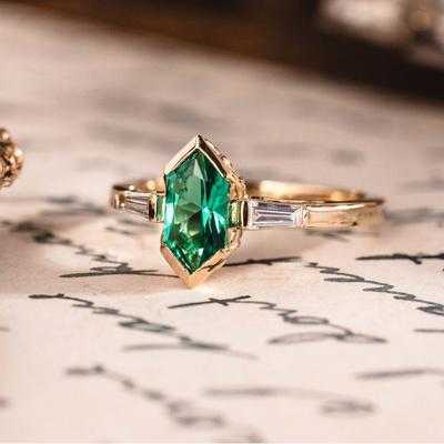 Gold ring with a green gemstone on an old document background