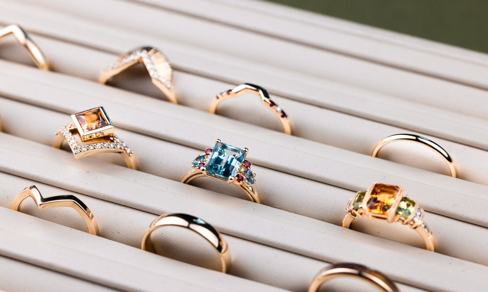 Gold rings with various gemstones on a white surface