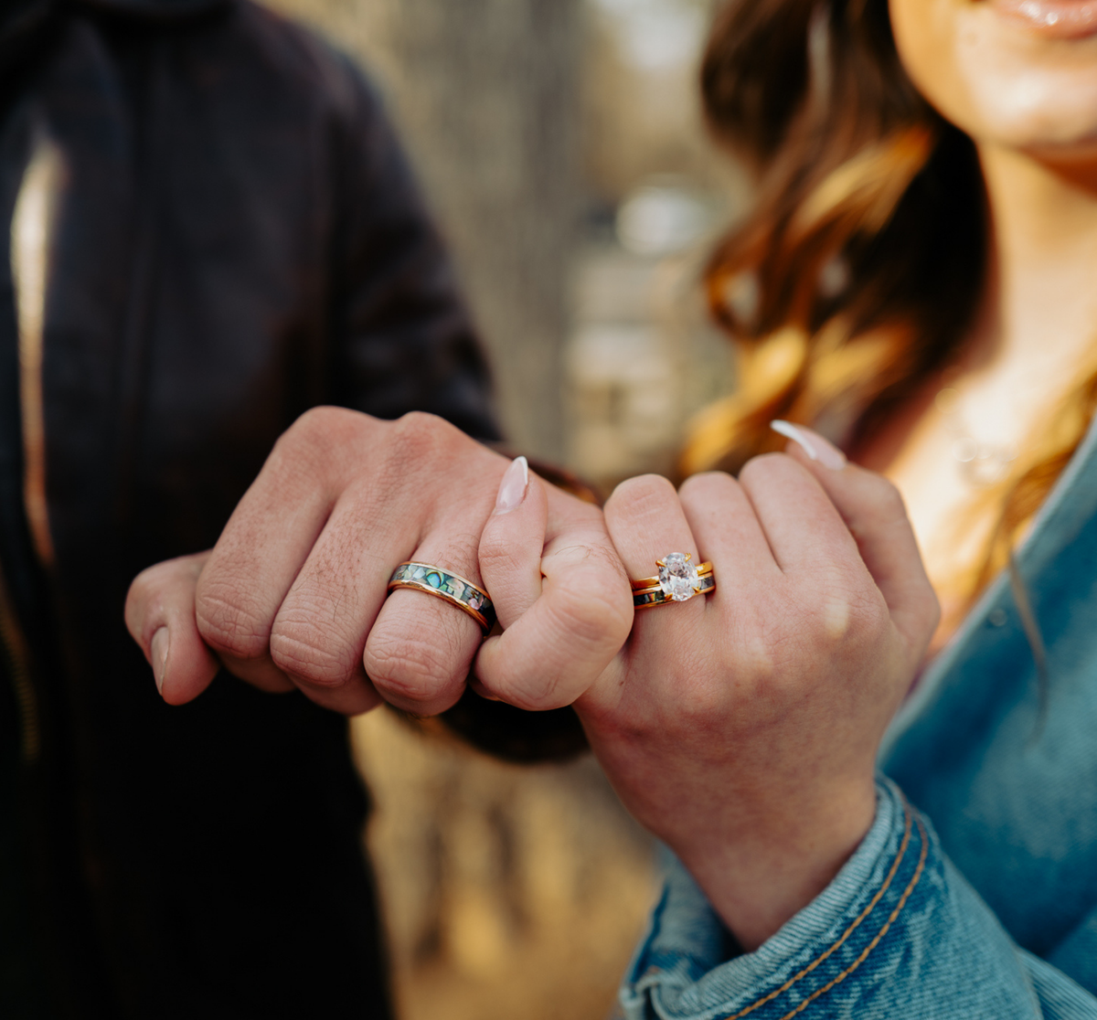 Couple holding hands wearing Jolene engagement ring and Pāua abalone gold bands