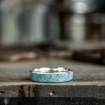 Silver ring with turquoise inlay on a wooden surface
