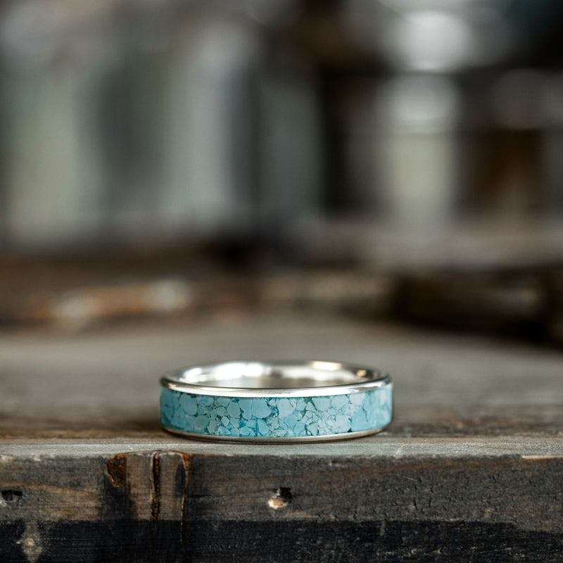 Silver ring with turquoise inlay on a wooden surface