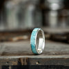 Silver ring with turquoise inlay on a wooden surface
