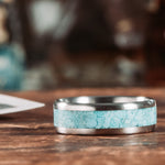 Titanium ring with turquoise inlay on a wooden surface