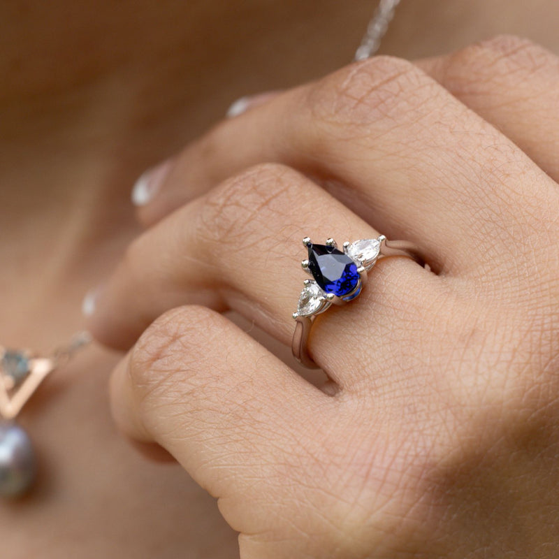 blue-sapphire-pear-cut-three-stone-engagement-ring-with-diamond-accents