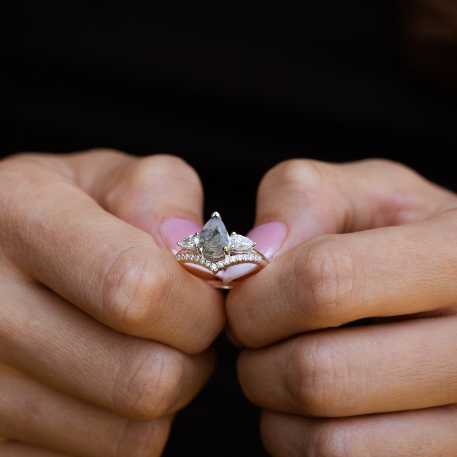 Close-up video of The Liora white gold ring worn on hand, featuring a pear-shaped moss agate center stone framed by two pear-shaped diamond side stones, with smaller diamond accents set beneath for added sparkle