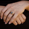 beatrix-yellow-gold-oval-moss-agate-ring-on-hand-dark-background