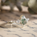 Three-quarter view of The Liora white gold ring showcasing a pear-shaped moss agate center stone framed by pear-shaped diamond side stones and smaller diamond accents beneath.