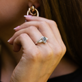 Lifestyle view of The Liora white gold ring worn on hand, featuring a pear-shaped moss agate center stone surrounded by pear-shaped and smaller diamond accents.