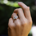 Outdoor close-up of The Liora white gold ring worn on hand, highlighting the pear-shaped moss agate center stone, pear-shaped diamond side stones, and delicate diamond accents underneath.