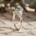 Side profile of The Liora white gold ring showing the raised pear-shaped moss agate setting, pear-shaped diamond side stones, smaller diamond accents underneath, and polished band.