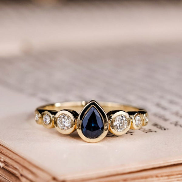 the-lyra-bezel-set-pear-cut-blue-sapphire-engagement-ring-diamond-accents