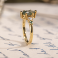 Side profile of The Titania yellow gold ring, showing the raised marquise moss agate setting, accent stone details, and polished yellow gold band.