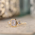 three-stone-emerald-cut-diamond-engagement-ring-round-diamond-accents-bezel-setting-the-marcelline-rustic-and-main