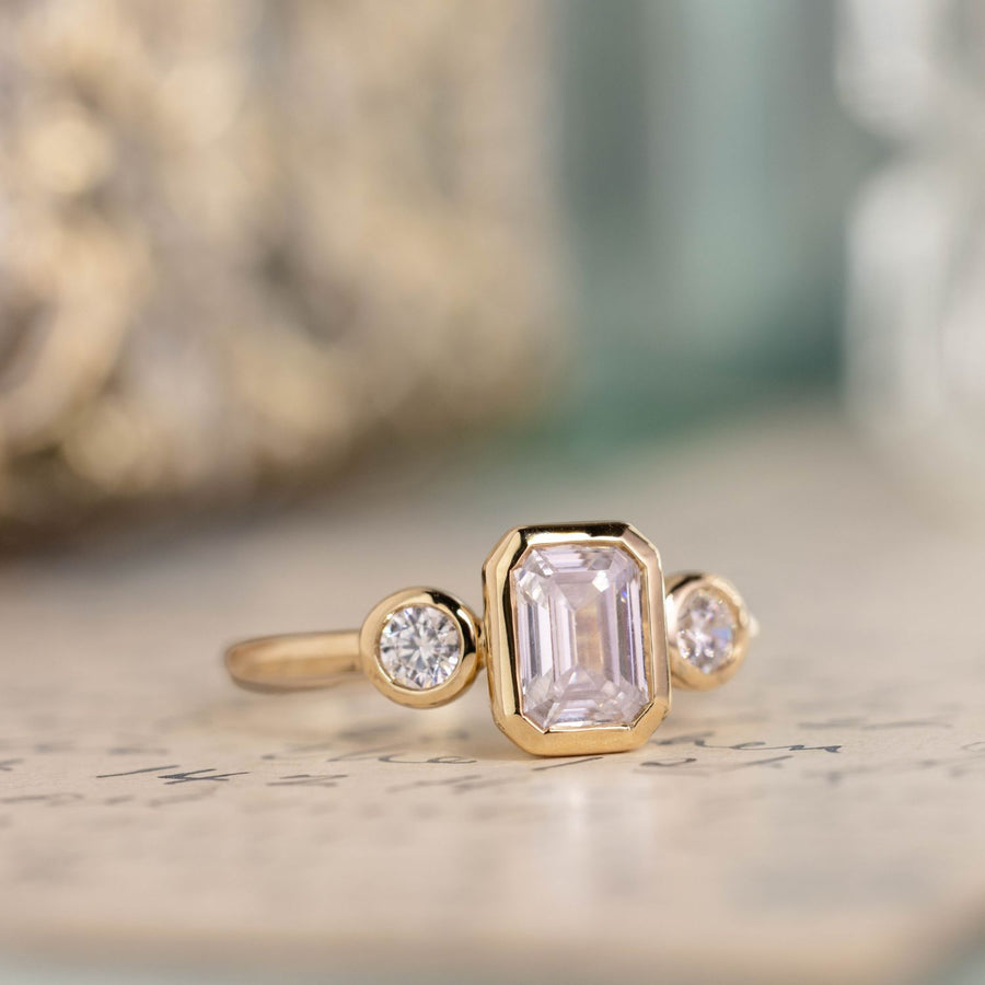 three-stone-emerald-cut-diamond-engagement-ring-round-diamond-accents-bezel-setting-the-marcelline-rustic-and-main